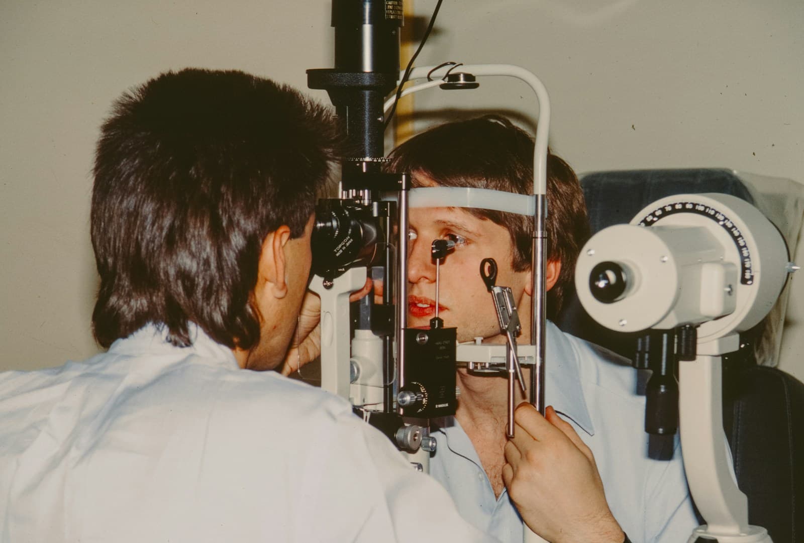 Eye doctor examining a patient with a slit-lamp instrument